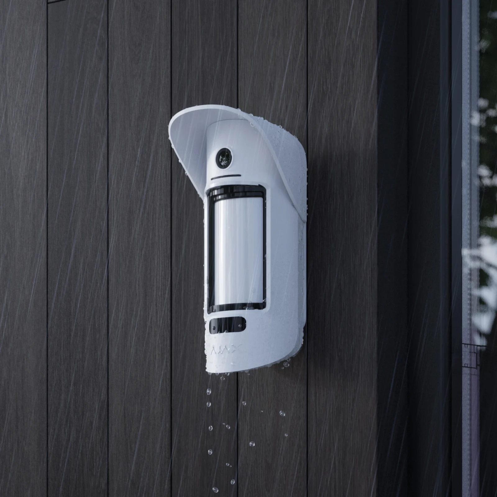 MotionCam Outdoor Bewegungsmelder außen an einer Holzfassade im Regen montiert